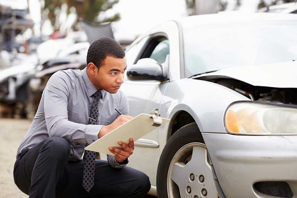 Person reviewing a denial letter, insurance policy, photographs, and organized claim documents at a desk.